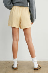 woman wearing yellow striped shorts with an elastic waistband, standing with her back to the camera