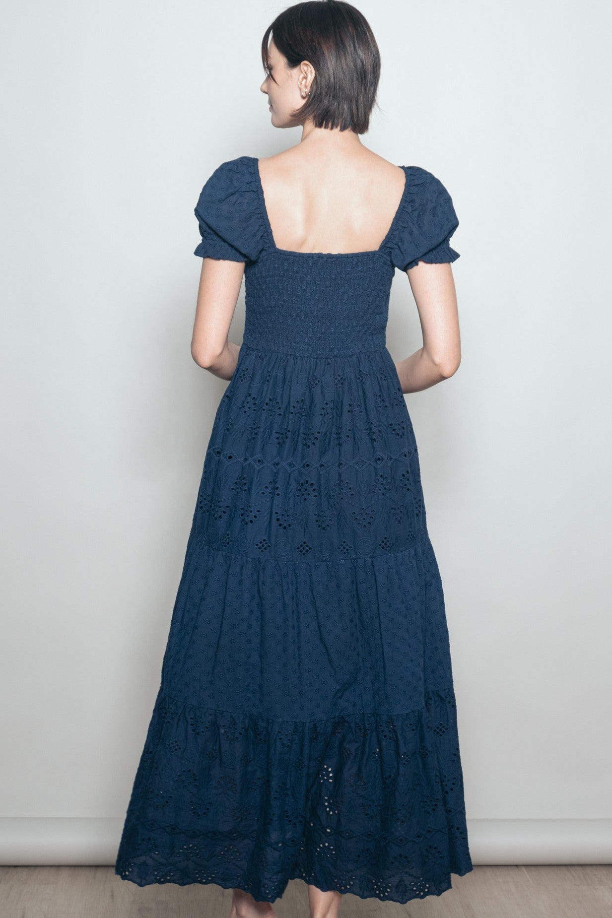 woman wearing a navy blue maxi dress with a smocked bodice and puff sleeves, shown from the back