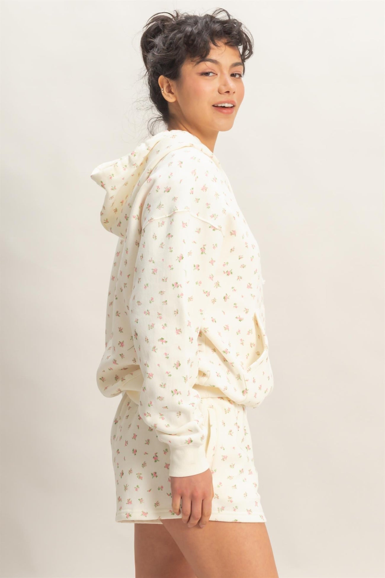 woman wearing a cream floral print hoodie with matching shorts