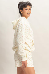 woman wearing a cream floral print hoodie with matching shorts