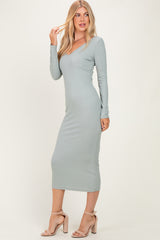 woman wearing a long sleeve ribbed midi dress in soft green with a deep v-neckline and fitted silhouette
