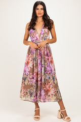woman wearing a floral print maxi dress with a deep V-neckline and a fitted waist, paired with strappy heels