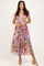 woman wearing a floral print maxi dress with a deep V-neckline and a fitted waist, paired with strappy heels