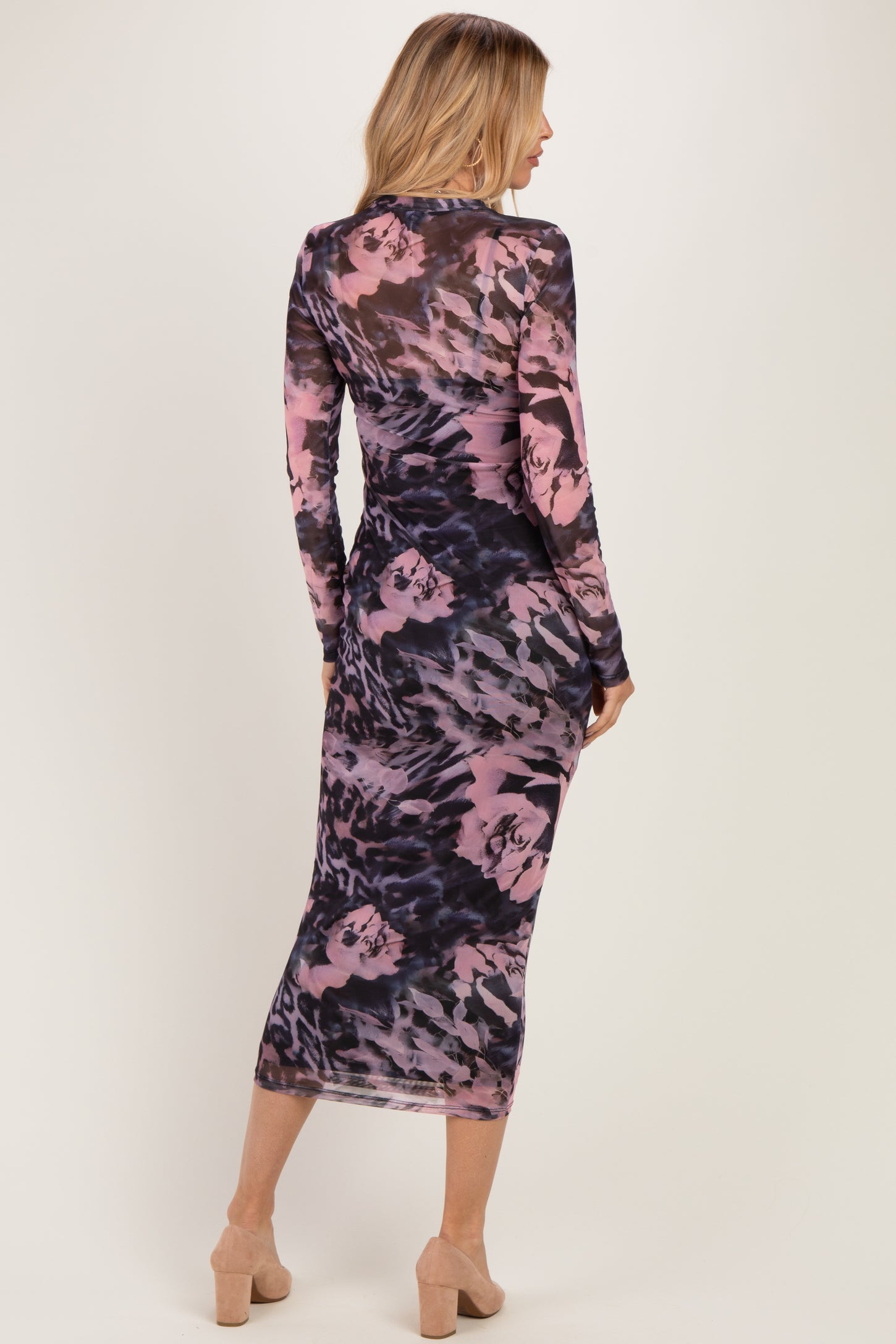 woman wearing a long sleeve bodycon dress in a purple and black abstract print, showing a form-fitting silhouette