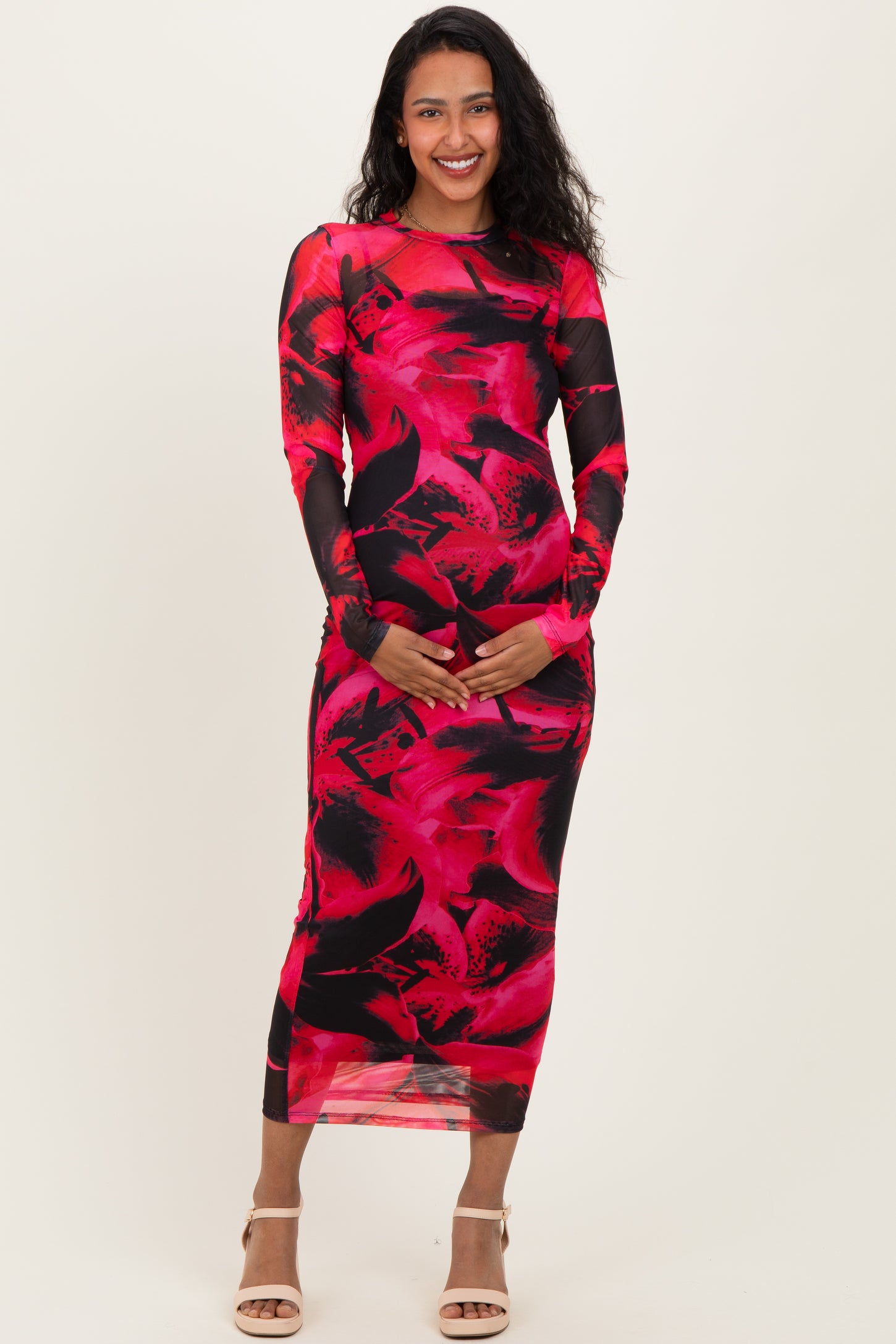 woman wearing a red and black floral long sleeve maternity dress and holding her baby bump