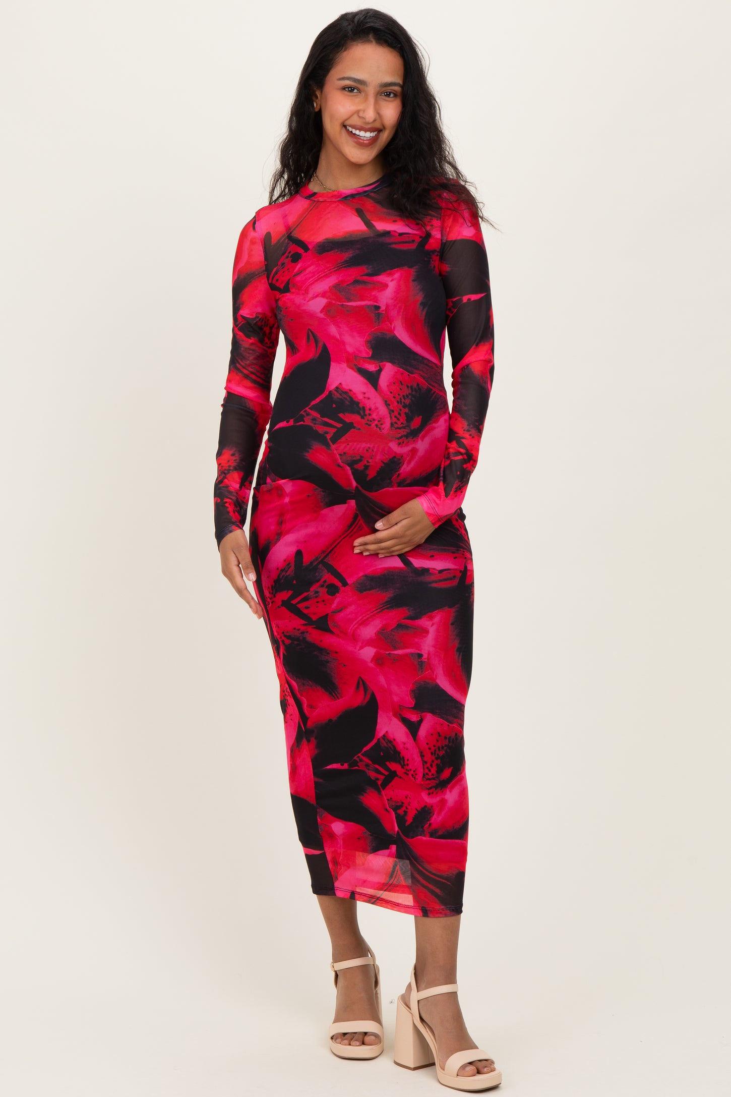 woman wearing a long sleeve pink and black floral print maternity dress and holding her baby bump