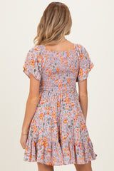 woman wearing a floral smocked maternity dress with flutter sleeves and a ruffled hem, showing the back view
