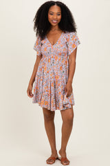 woman wearing a floral print v-neck short sleeve dress with a flowy skirt and smiling at the camera