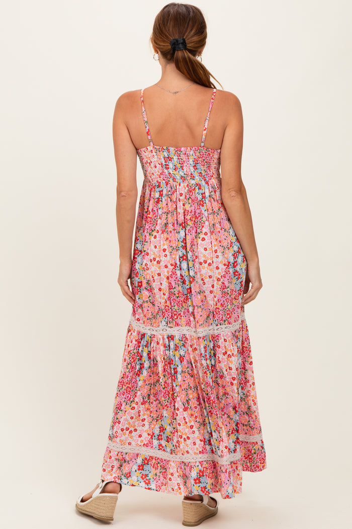 woman wearing a floral pink maxi dress with thin straps and a tiered skirt