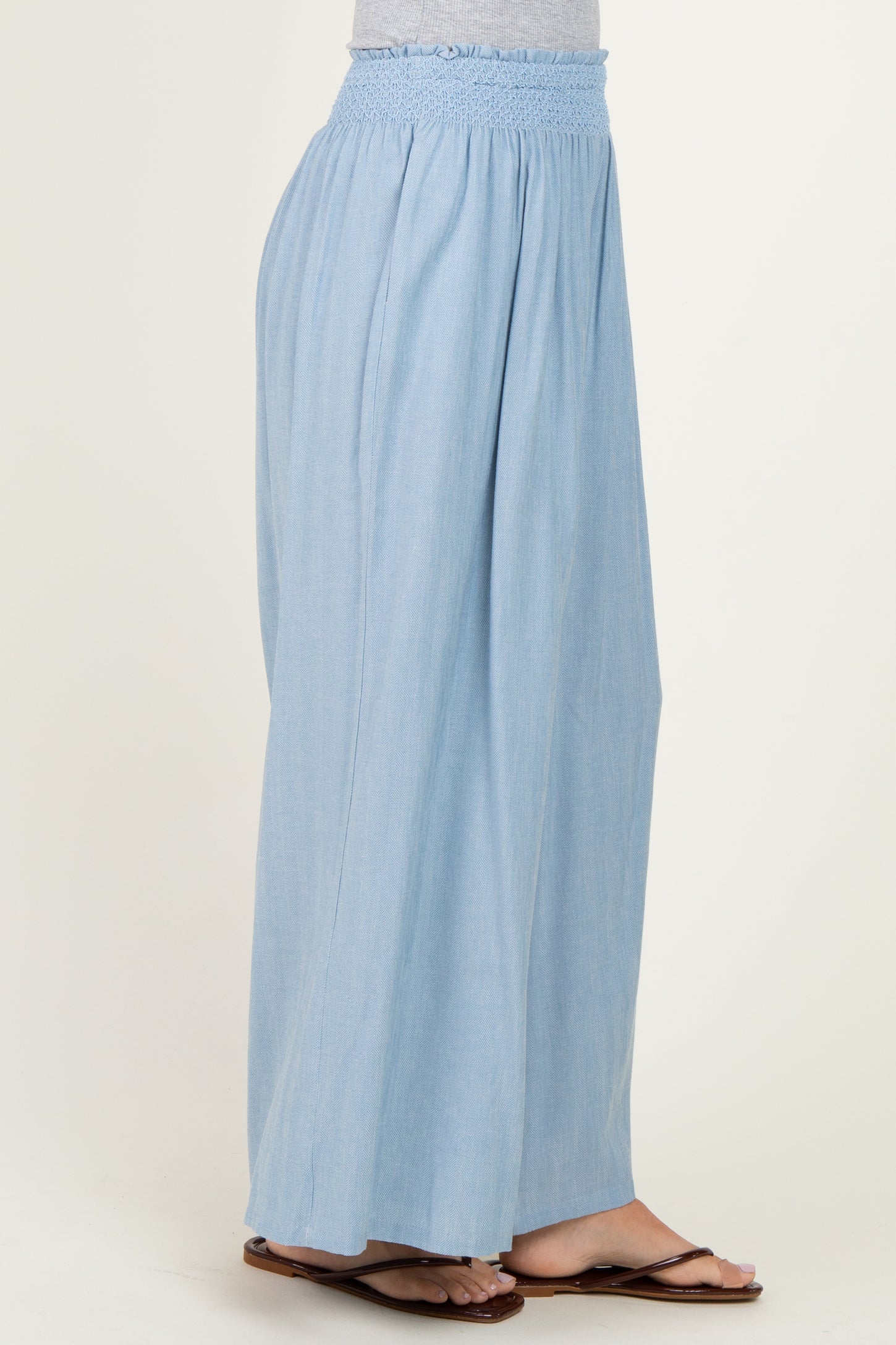 woman wearing light blue wide-leg pants with a smocked waistband and sandals