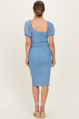 woman wearing a light blue polka dot maternity dress with short puff sleeves and a fitted silhouette, showing her back