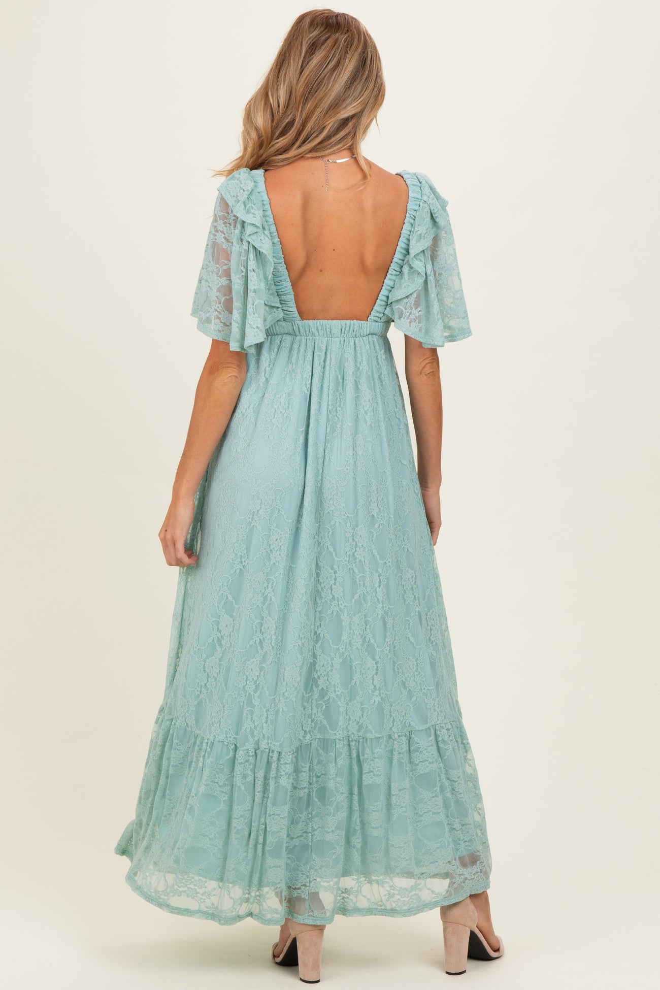 woman wearing a light blue lace maternity maxi dress with flutter sleeves and open back, showing a baby bump