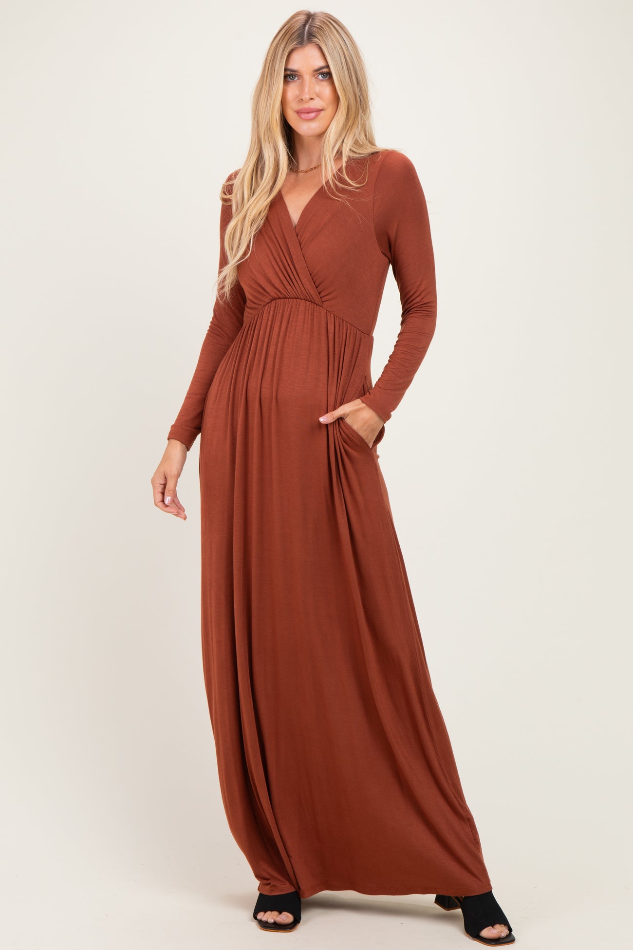 woman wearing a rust long sleeve maxi dress with a wrap style and side pockets