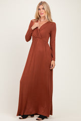 woman wearing a rust long sleeve maxi dress with a wrap style and pleated details