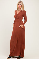 woman wearing a rust long sleeve maxi dress with a v-neck and side pockets