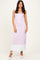 woman wearing a light pink ribbed maxi dress with white hem and decorative buttons, standing with one hand on her hip
