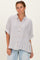 woman wearing a striped button-up shirt with short sleeves and relaxed fit, styled with light blue jeans