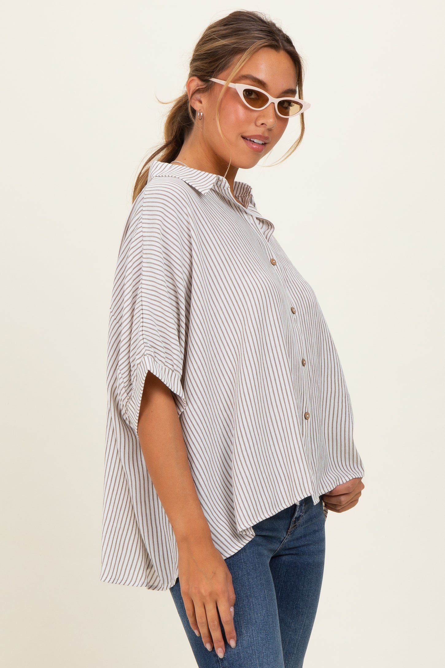 woman wearing a striped oversized button-up shirt with short sleeves and light denim jeans