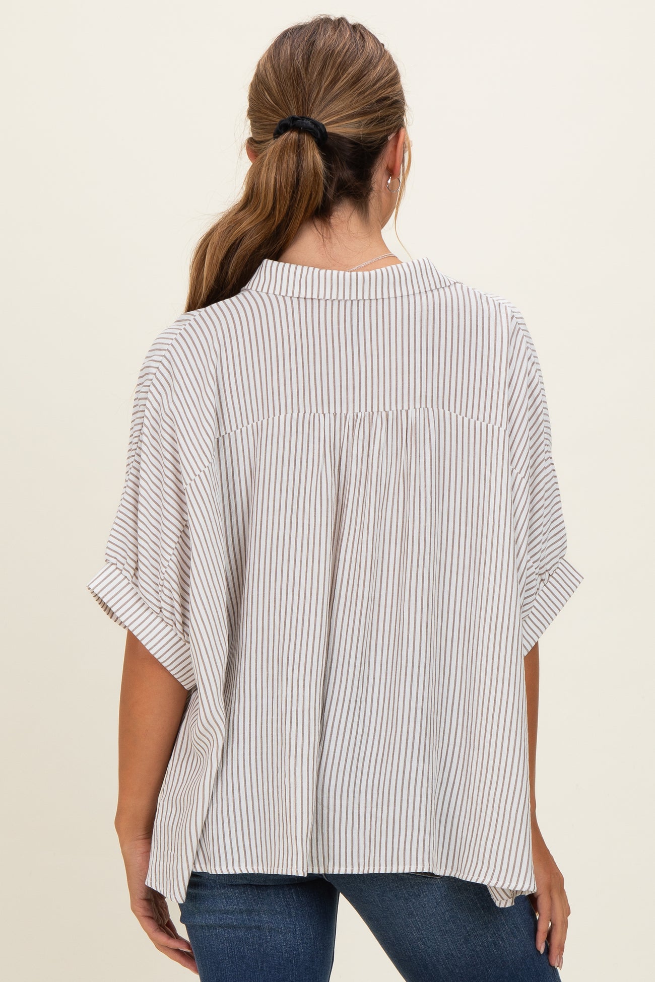 woman wearing a beige and white striped short sleeve blouse with a relaxed fit and back yoke detail