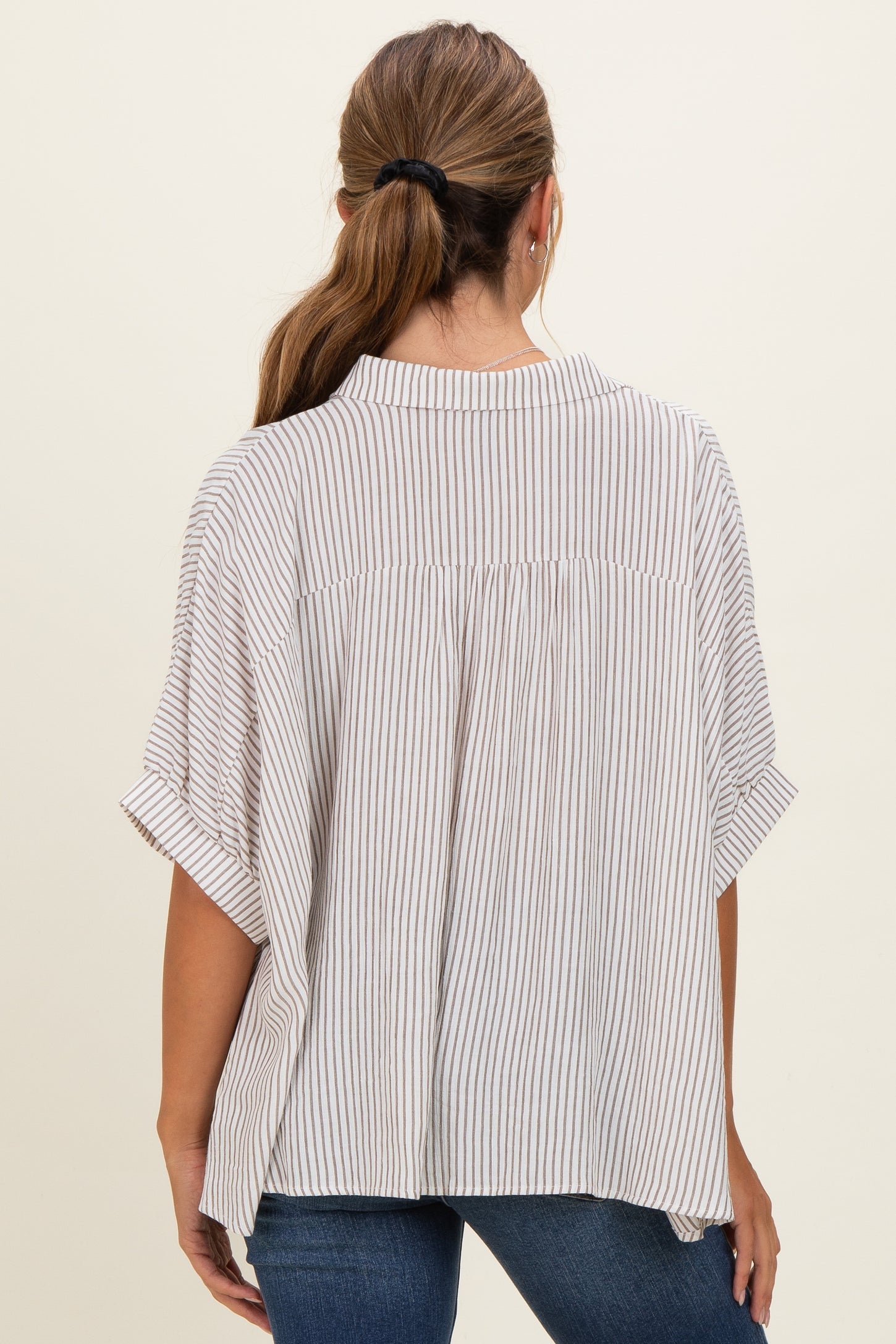 woman wearing a beige and white striped short sleeve blouse with a relaxed fit and back yoke detail