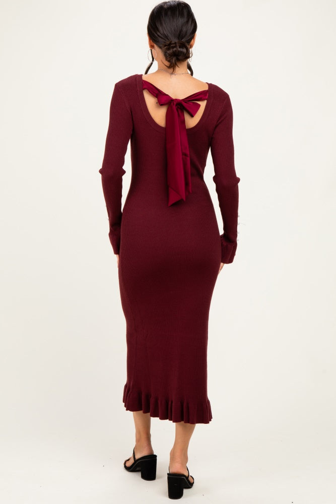 woman wearing a burgundy ribbed knitted midi dress with a back tie detail and ruffled hem