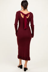 woman wearing a burgundy ribbed knitted midi dress with a back tie detail and ruffled hem