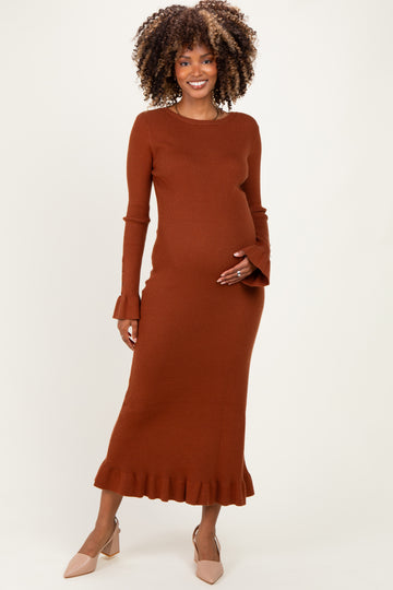 woman wearing a rust ribbed maternity dress with ruffled hem and bell sleeves, showing her baby bump