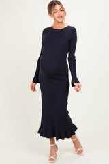 woman wearing a navy ribbed maternity dress with long sleeves and a ruffled hem, showcasing her baby bump