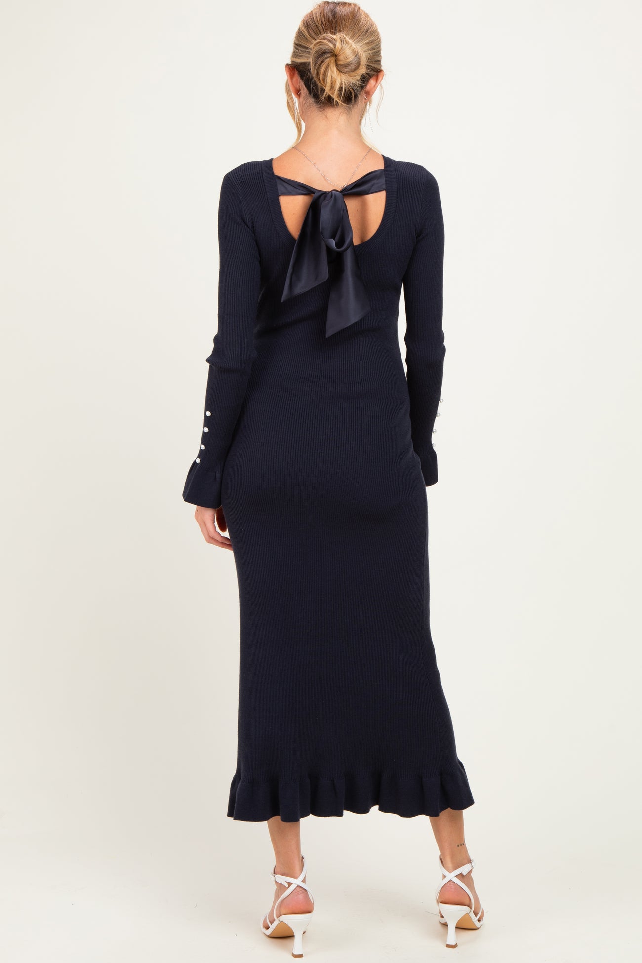 woman wearing a navy blue long sleeve maternity dress with a bow detail at the back and ruffled hem