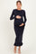 woman wearing a navy blue ribbed maternity dress with bell sleeves and a ruffle hem, holding her baby bump