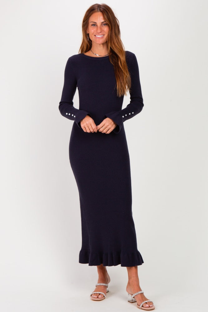 woman wearing a navy blue long sleeve ribbed knit dress with ruffle hem and button details on the sleeves