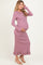 woman wearing a lavender ribbed maternity dress with ruffled hem and long sleeves, showing her baby bump