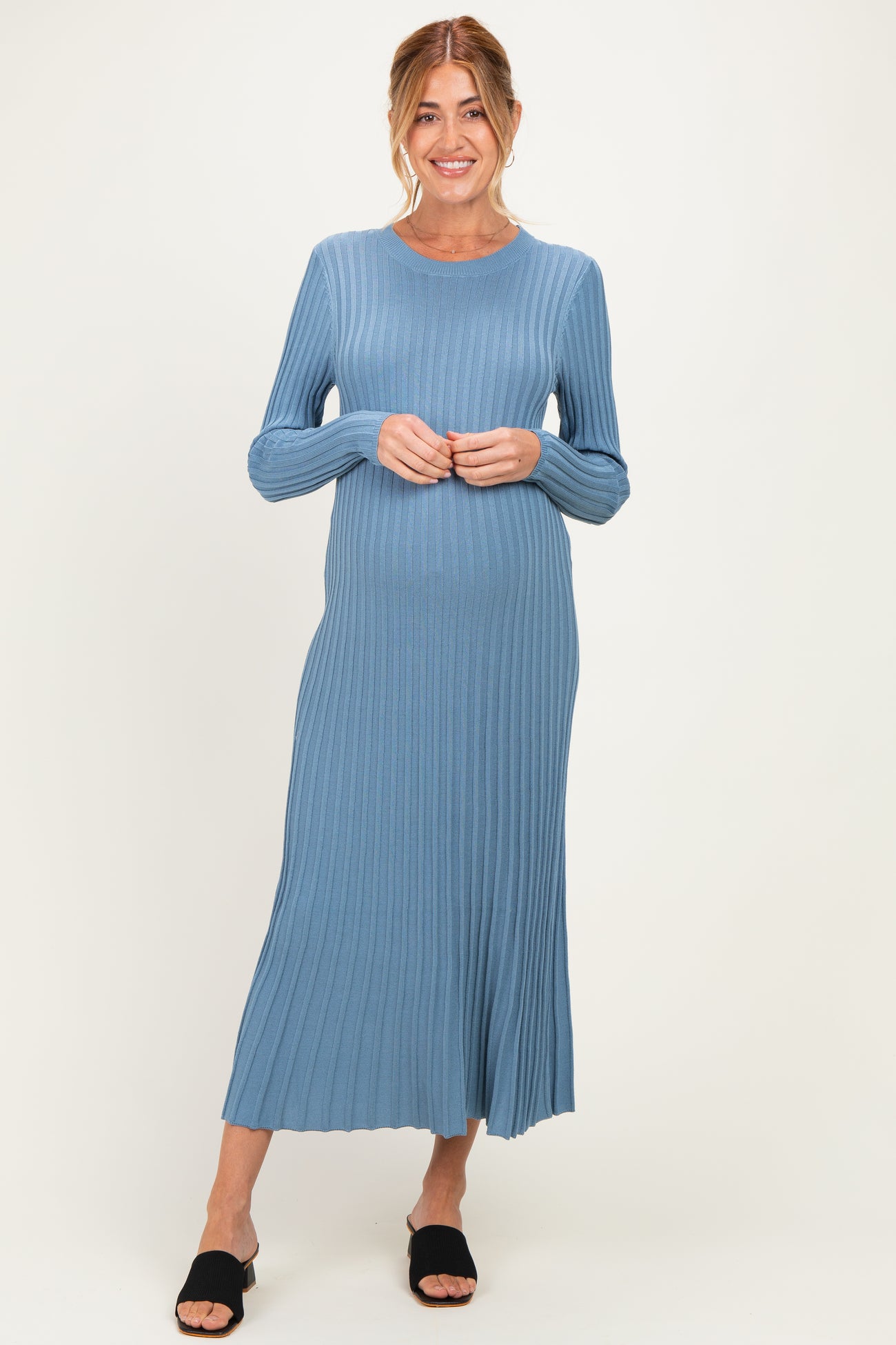woman wearing a light blue ribbed maternity dress that flows to the mid-calf and showcasing her baby bump