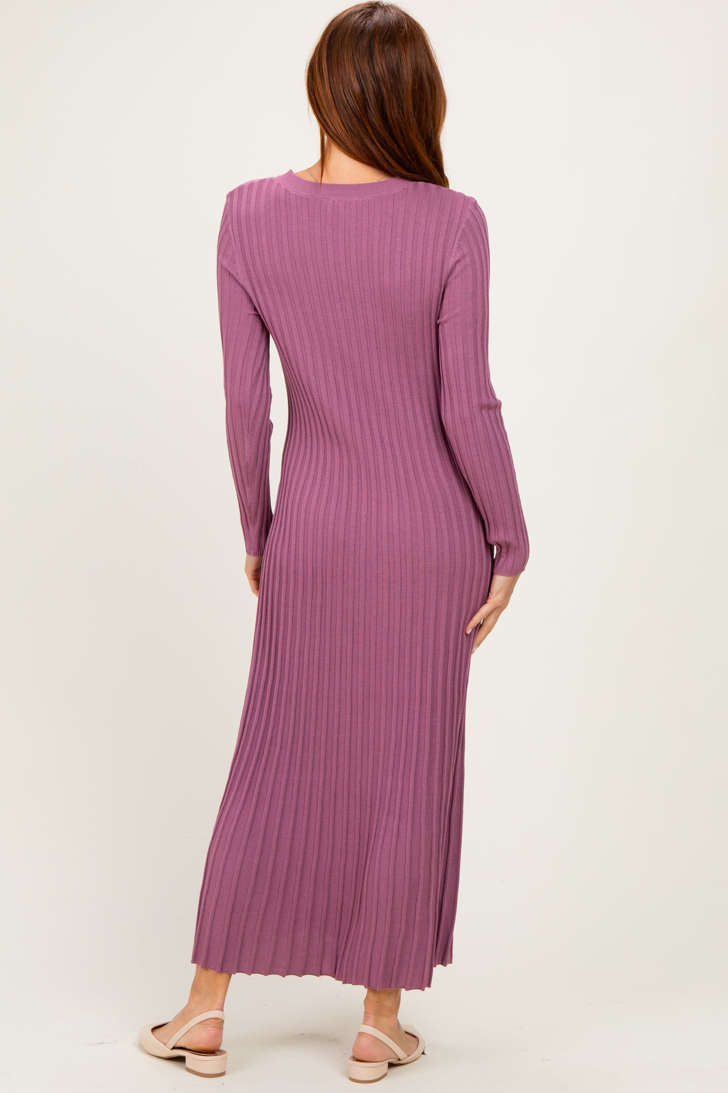 woman wearing a mauve long sleeve ribbed maxi dress, showcasing a fitted silhouette and flowy hem from the back