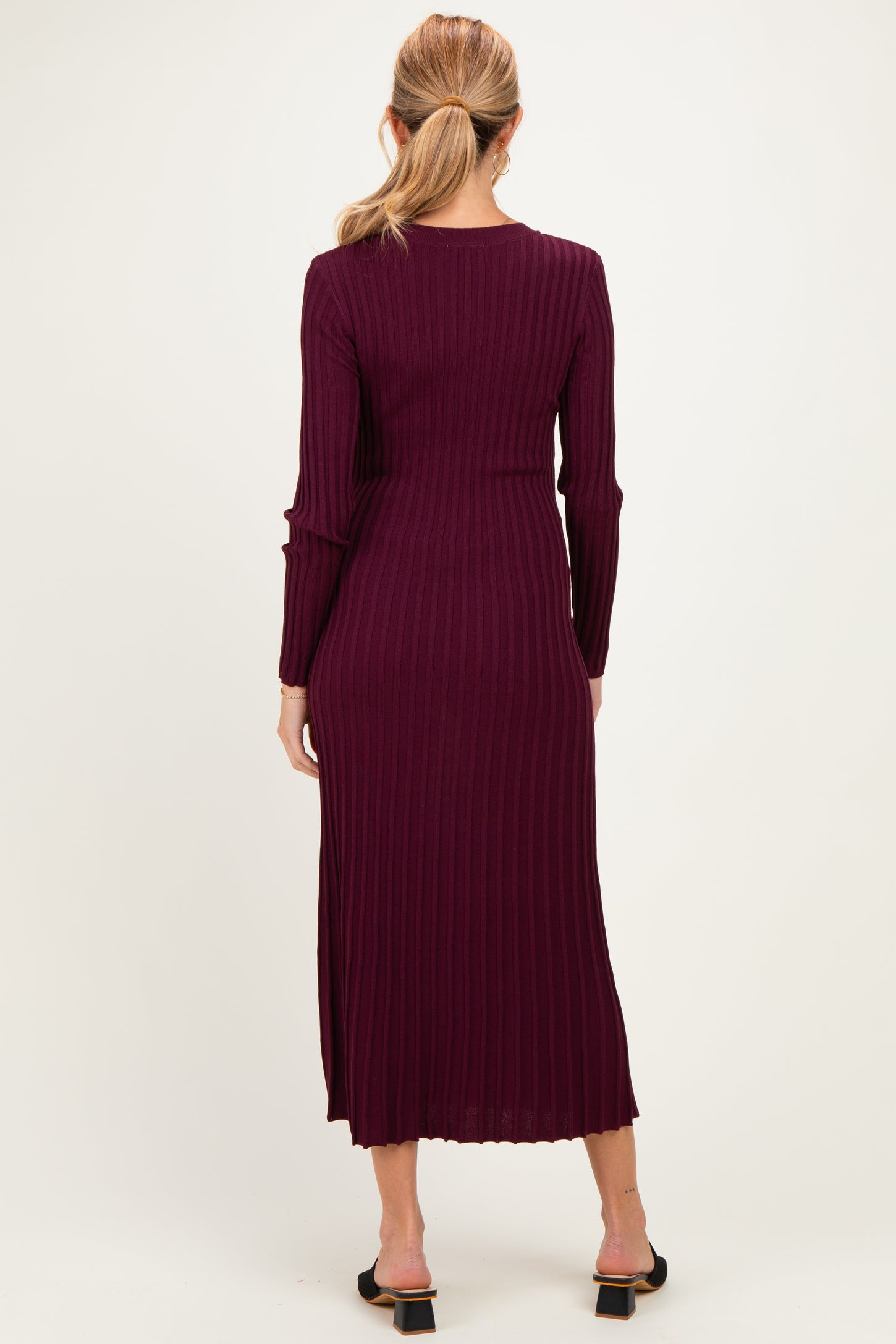 woman wearing a burgundy ribbed maternity dress with long sleeves and a midi length, showing the back view
