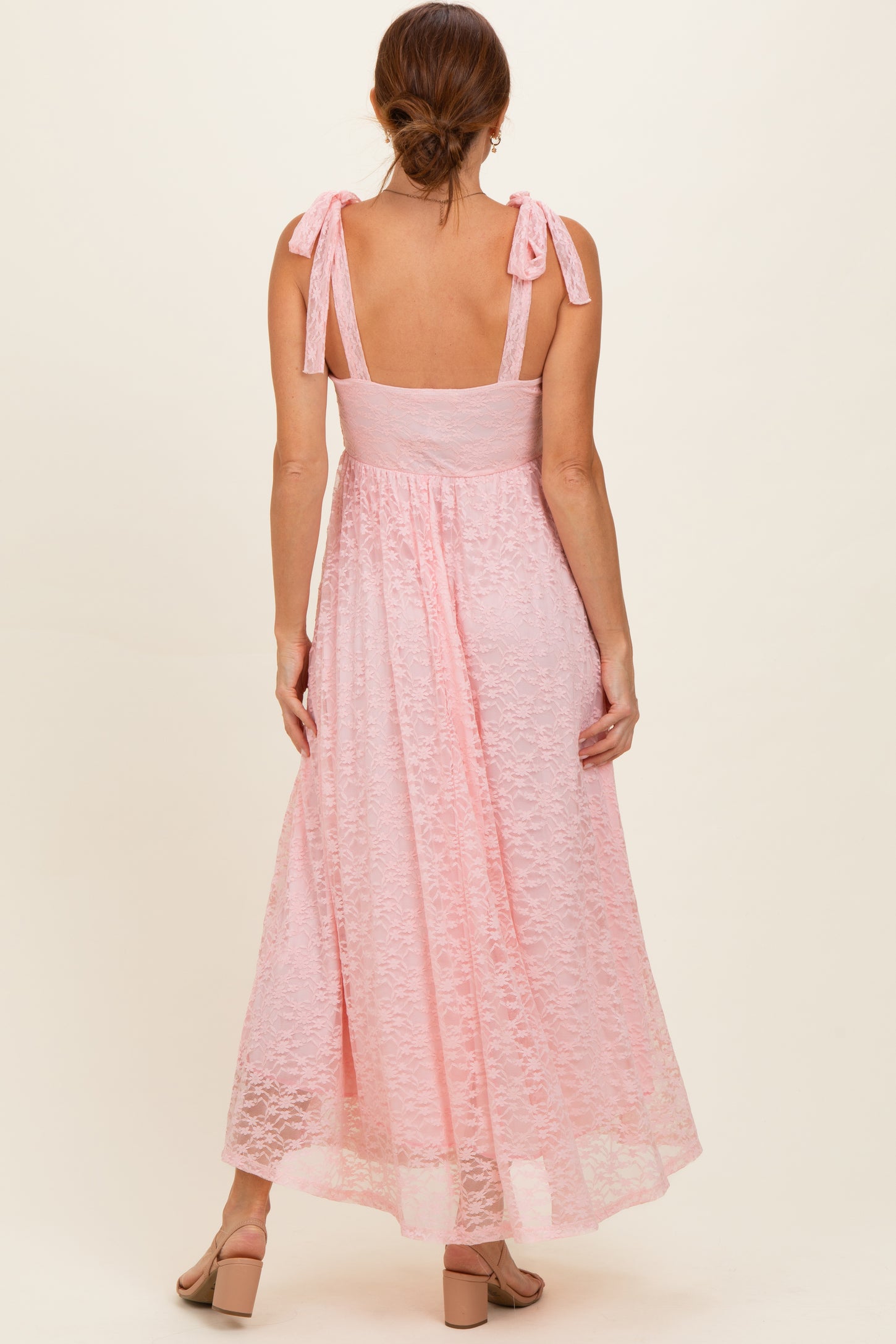 woman wearing a pink maxi dress with tie shoulder straps and a fitted bodice, shown from the back