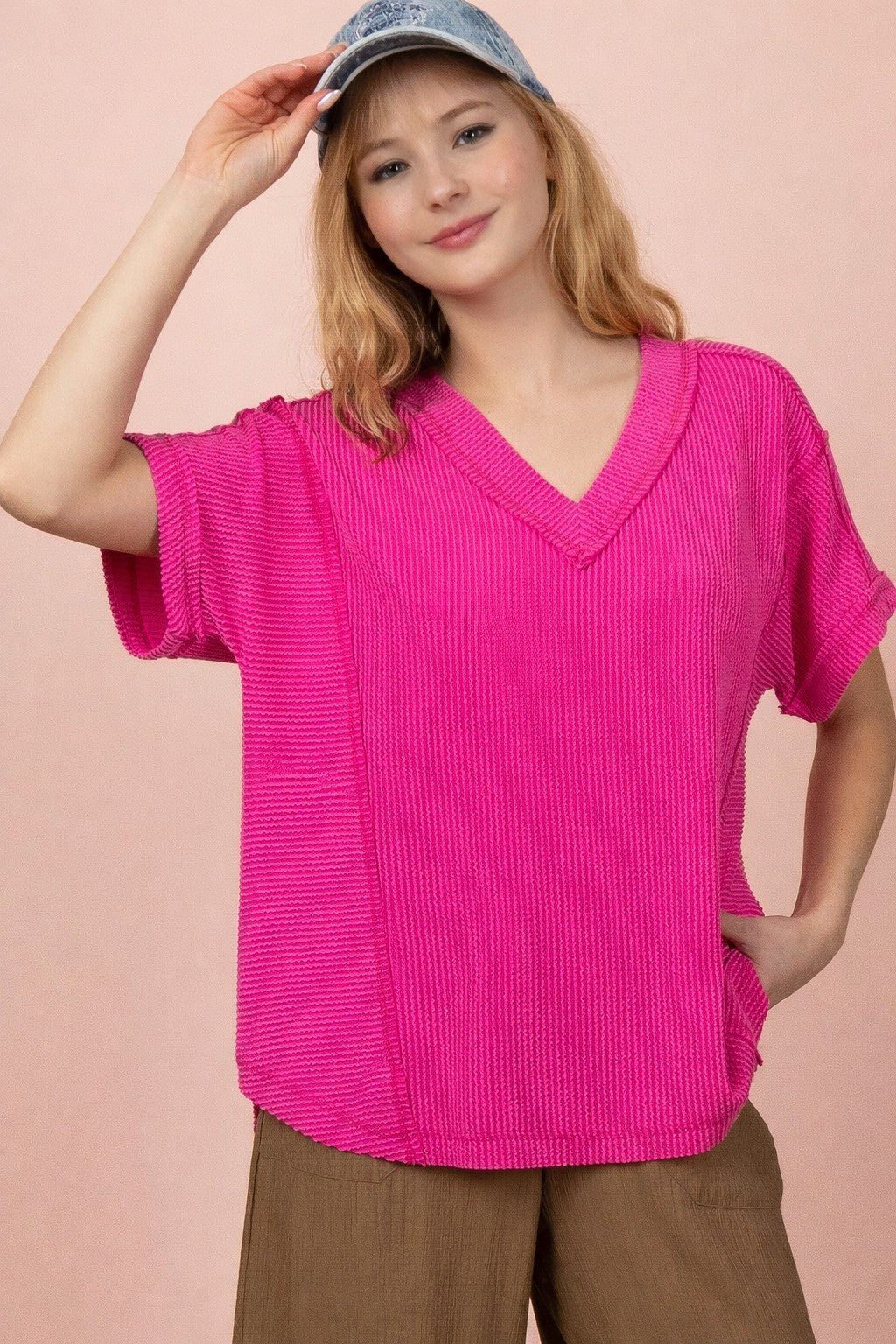 woman wearing a bright pink short sleeve v-neck top with textured fabric and a relaxed fit