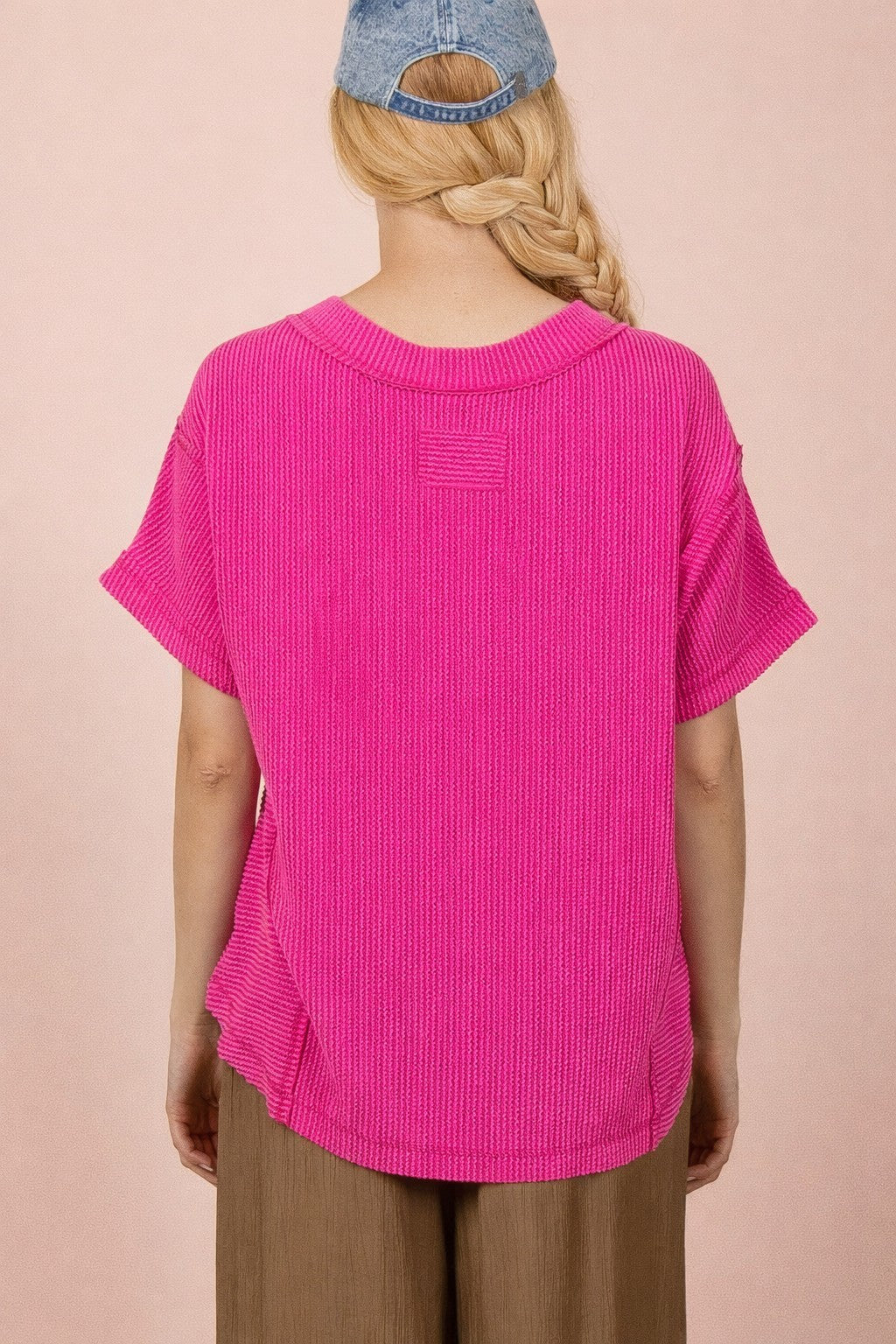 woman wearing a vibrant pink oversized knit top with short sleeves and a relaxed fit, viewed from the back