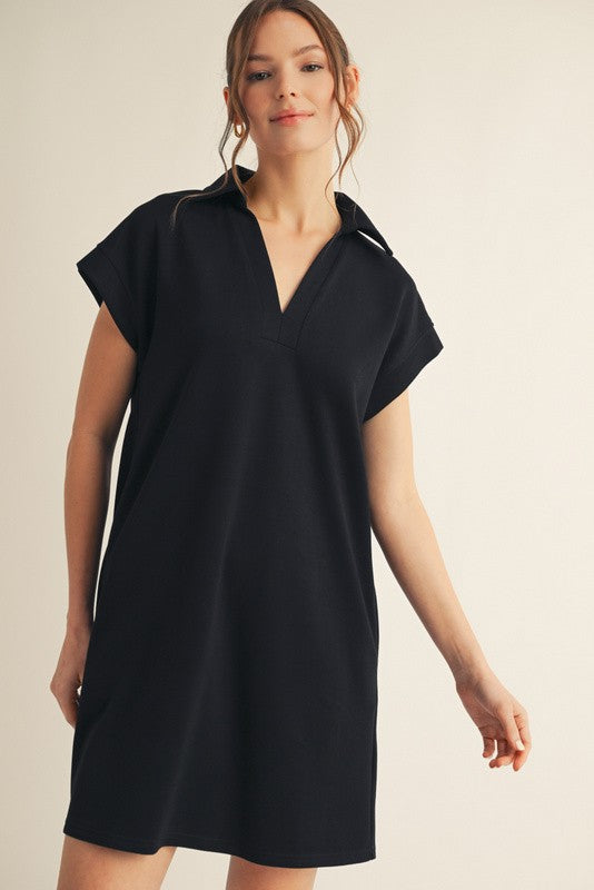 woman wearing a black short sleeve polo dress with a v-neck and relaxed fit