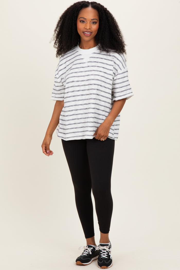 woman wearing a striped oversized gray and white t-shirt with black leggings and sneakers