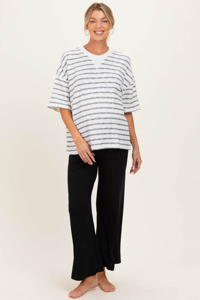 woman wearing a striped maternity top and black lounge pants, showcasing a baby bump