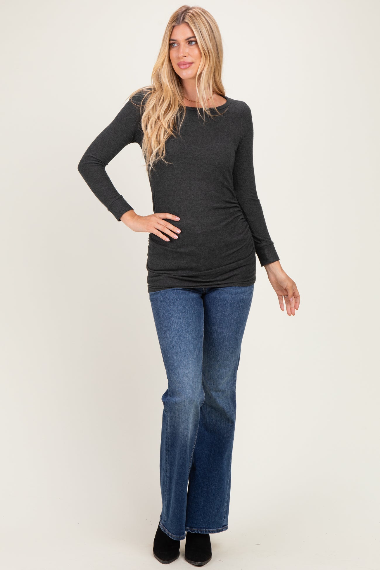 woman wearing a dark gray long sleeve top paired with flared denim jeans