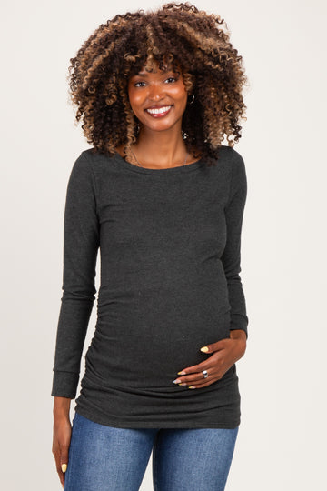 woman wearing a dark grey long sleeve maternity top and holding her baby bump