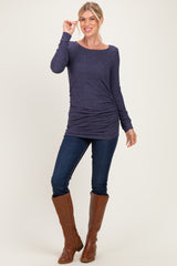 woman wearing a navy long sleeve top with ruched sides, paired with skinny jeans and brown knee-high boots