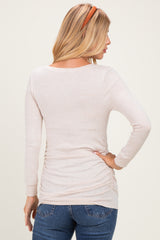 woman wearing a light pink long sleeve top with gathered sides, styled with dark wash jeans and a headband