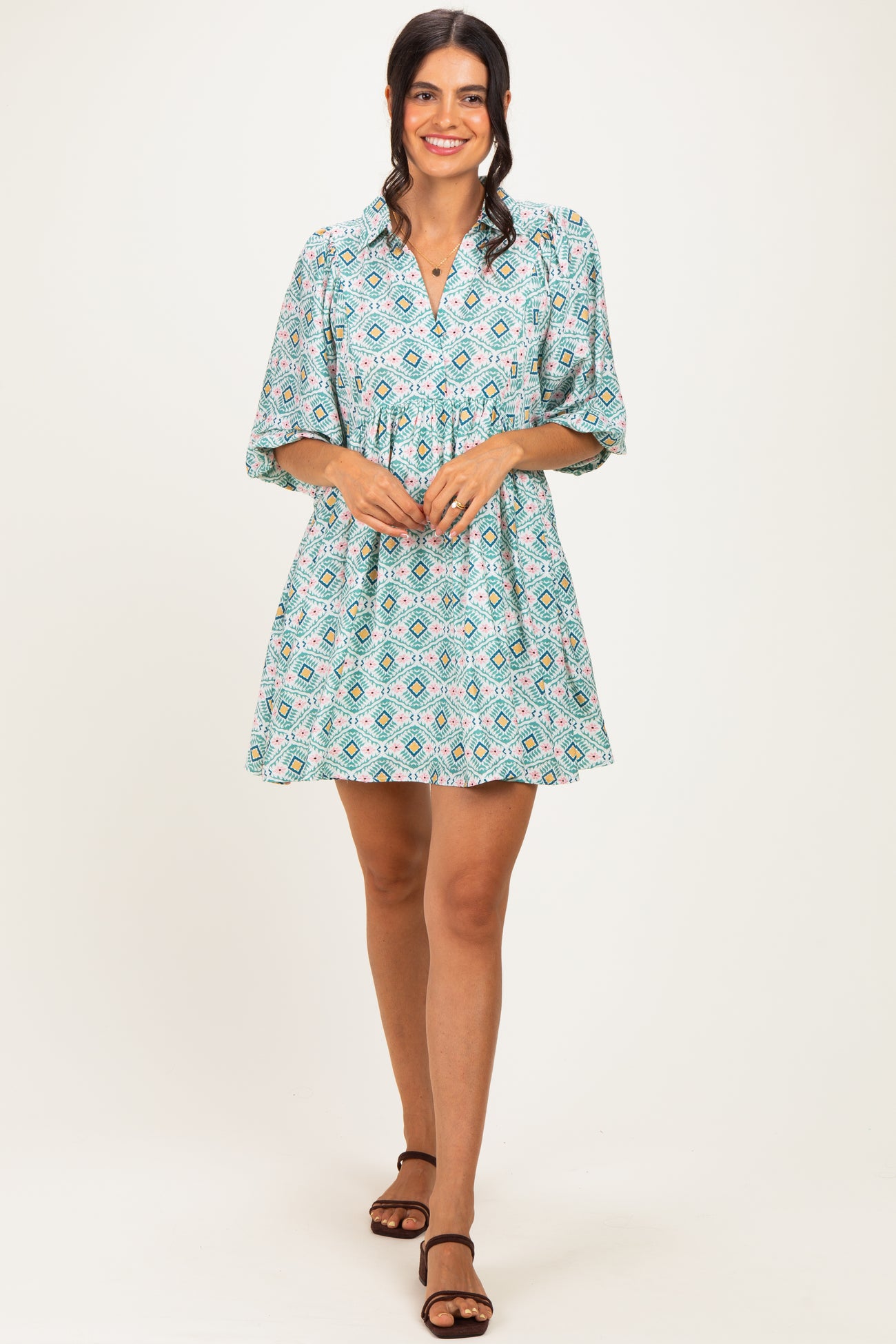woman wearing a teal patterned short dress with a V-neck and three-quarter sleeves