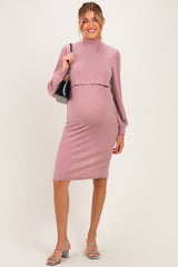woman wearing a pink ribbed maternity dress with long sleeves and a fitted silhouette, showing her baby bump