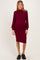 woman wearing a burgundy ribbed maternity dress with long puff sleeves and a fitted silhouette, showing her baby bump