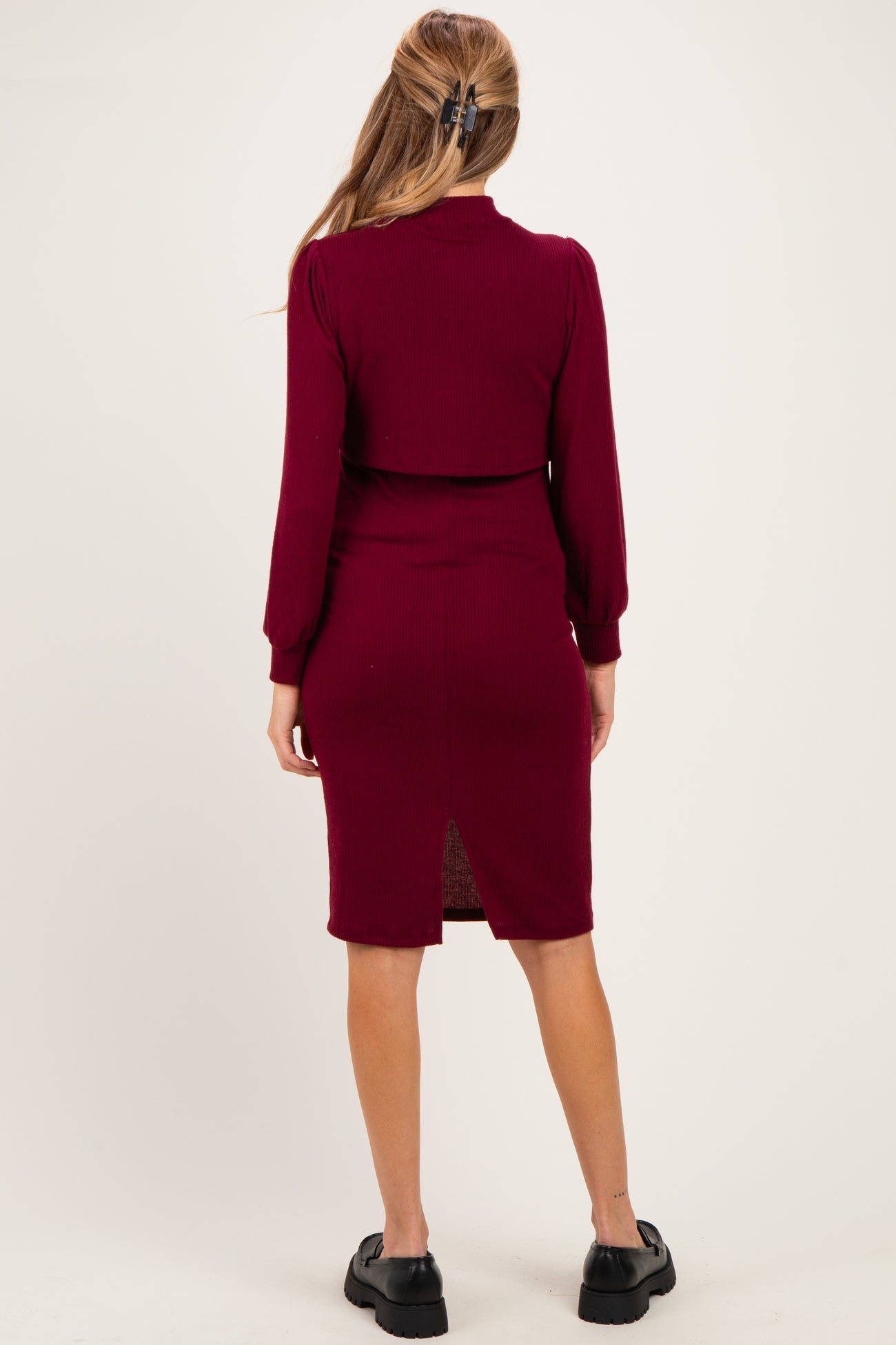 woman wearing a burgundy ribbed maternity dress with a back slit and long sleeves