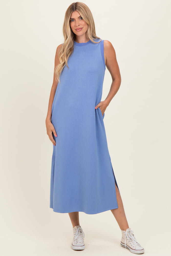 woman wearing a sleeveless light blue maxi dress with side pockets and side slits, styled with white sneakers